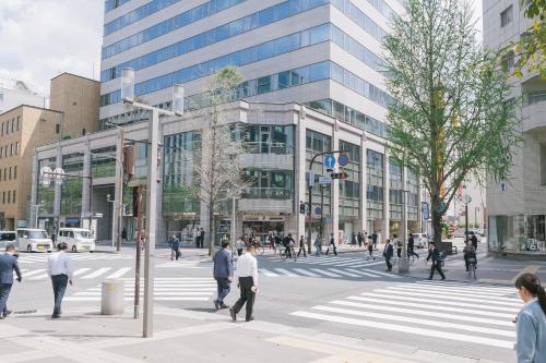 a group of people crossing a street in front of a building at WeBase Hakata Hostel in Fukuoka