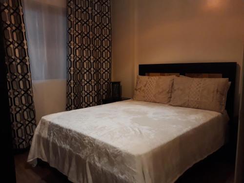 a bedroom with a bed with white sheets and curtains at Outlook Ridge Residences in Baguio