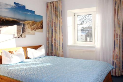 キュールングスボルンにあるFewo-Perner Strandschlösschenのベッドルーム1室(青い掛け布団、窓付)