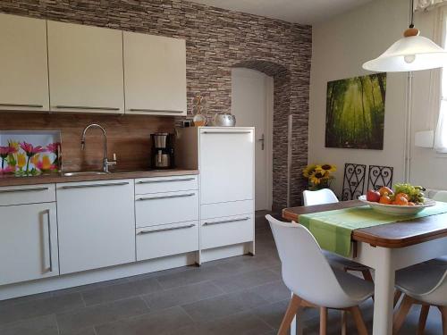 a kitchen with white cabinets and a table with a bowl of fruit at Mia Casa in Morsbach