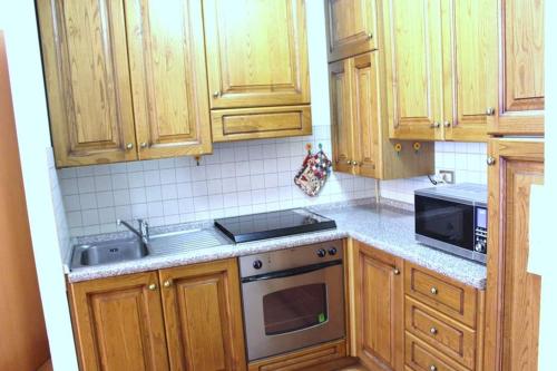 a kitchen with wooden cabinets and a stove top oven at Appartamento di Viola & Elia in Predazzo