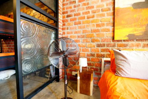 een kamer met een ventilator naast een bakstenen muur bij Homestay Shah Alam by Rose - Studio Unit in Shah Alam