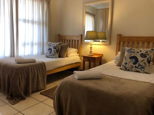 a bedroom with two beds and a mirror and a lamp at Vista Bonita Apartments in Mossel Bay