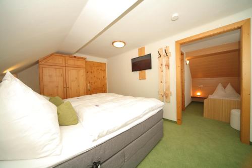 a bedroom with a large white bed and a television at Aignerhof in Haus im Ennstal