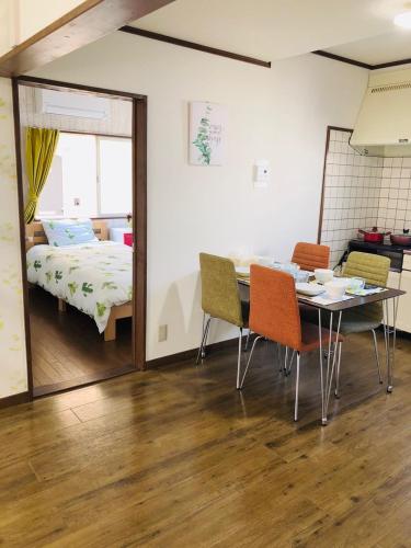 a dining room with a table and chairs and a bed at 201Keiko's Home 大空間2LDKロフト付きfree parking in Kasugabaru