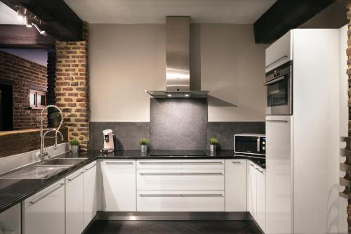 a kitchen with white cabinets and a brick wall at Appart-Hotel Léopold Liège Centre in Liège
