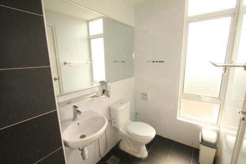 a white bathroom with a toilet and a sink at Ipoh Premium Homestay @ Majestic in Ipoh