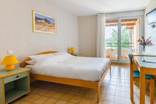 Un dormitorio con una cama y un escritorio y un balcón. en Azureva La Londe les Maures, en La Londe-les-Maures