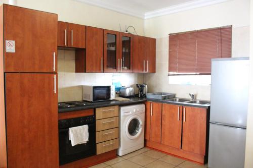 a kitchen with wooden cabinets and a washer and dryer at Vista Bonita Apartments in Mossel Bay