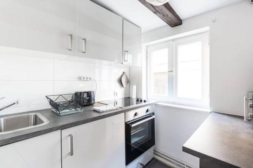 ストラスブールにあるCentral & Cosy Apartment Strasbourg City Centerのシンクとコンロのある白いキッチン