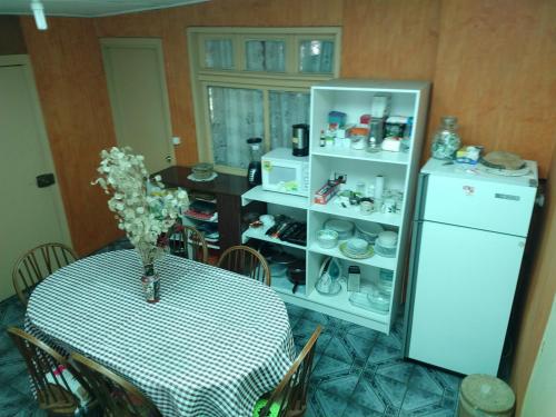 Una cocina con una mesa y un refrigerador blanco. en Cabana Caburgua, en Caburgua