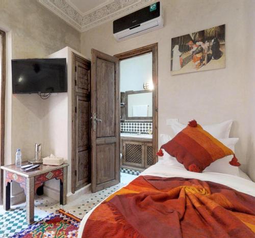 a bedroom with a bed and a television in a room at Riad Sania By Ghali in Marrakech