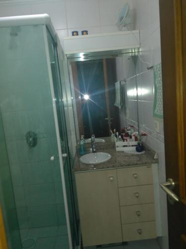 a bathroom with a sink and a shower with a mirror at Apartamento Centro Gramado in Gramado