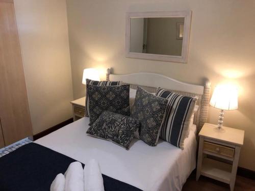 a bedroom with a bed with pillows and a mirror at Vista Bonita Apartments in Mossel Bay