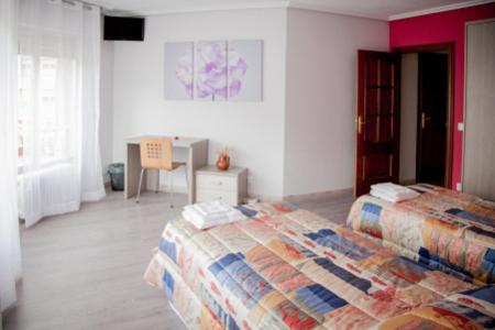 1 dormitorio con 2 camas y mesa. en Pensión Parque del Ebro, en Logroño