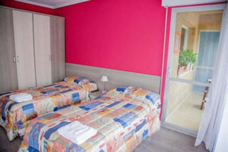 a bedroom with two beds and a pink wall at Pensión Parque del Ebro in Logroño