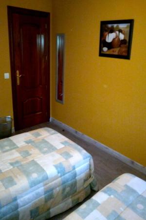 a bedroom with two beds in a room with yellow walls at Pensión Parque del Ebro in Logroño