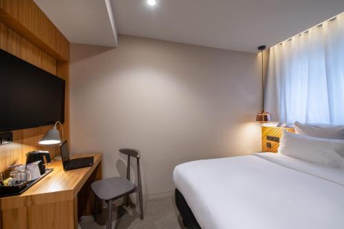 a hotel room with a bed and a desk with a laptop at 9Hotel Paquis in Geneva