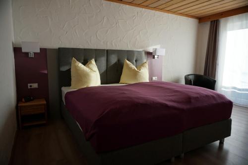 ein Schlafzimmer mit einem großen Bett mit lila Bettwäsche und Kissen in der Unterkunft Hotel Sonnenbichl in Halblech