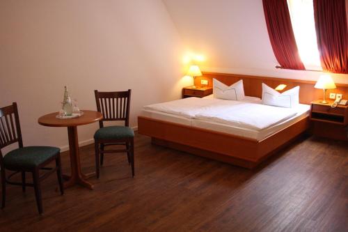 Schlafzimmer mit einem Bett, einem Tisch und Stühlen in der Unterkunft Landhotel Rügen in Stönkvitz