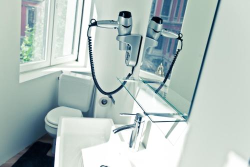 a bathroom with a sink and a mirror and a toilet at Appart-Hotel Léopold Liège Centre in Liège