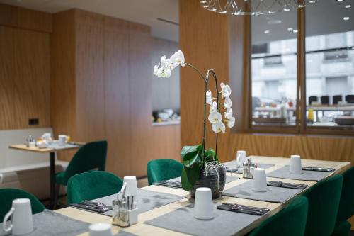 a table with green chairs and a vase with white flowers at 9Hotel Paquis in Geneva