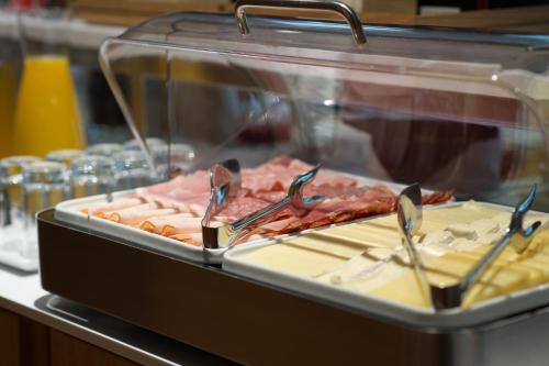 a display case with a bunch of meats and tongs at 9Hotel Paquis in Geneva