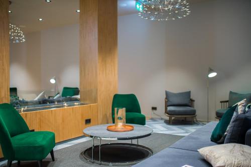 a waiting room with green chairs and a table at 9Hotel Paquis in Geneva