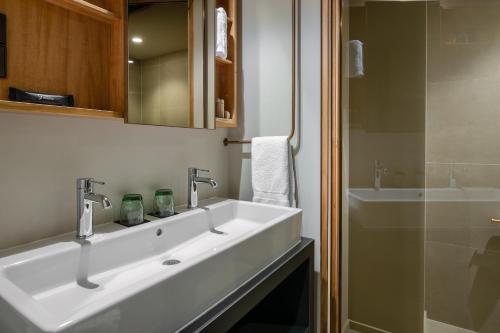 a white bathroom with a sink and a shower at 9Hotel Paquis in Geneva