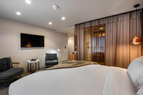 a bedroom with a bed and two chairs and a television at 9Hotel Paquis in Geneva
