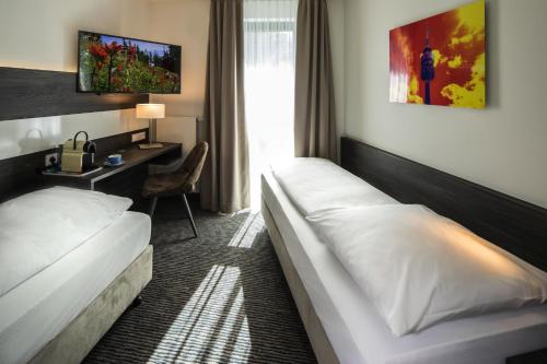 una camera d'albergo con 2 letti e una scrivania di Hotel Südstern a Monaco