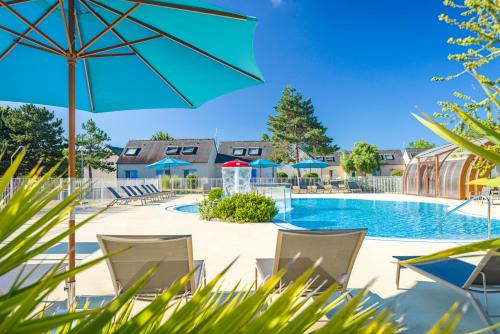 a swimming pool with chairs and an umbrella at Azureva Kerjouanno in Arzon