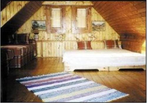 a attic room with a bed and a rug at Chalupa Alzbeta in Liptovský Ján