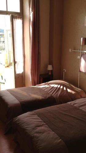 a bedroom with two beds and a window at Hôtel Restaurant Les oliviers in Nyons