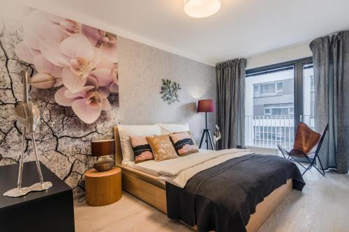 Prague Luxury Apartments Parking by Michal&Friends في براغ: غرفة نوم مع سرير وورود على الحائط