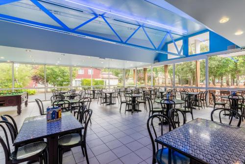 un restaurant vide avec des tables, des chaises et des fenêtres dans l'établissement Azureva Longeville, à Longeville-sur-Mer