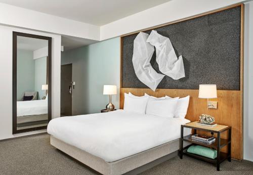 a bedroom with a large white bed and a mirror at 21c Museum Hotel Louisville in Louisville