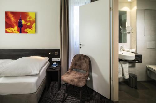 ein Schlafzimmer mit einem Bett und einem Stuhl neben einem Waschbecken in der Unterkunft Hotel Südstern in München