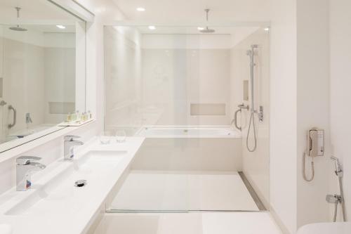 a white bathroom with two sinks and a shower at B Hotel Brasilia in Brasilia