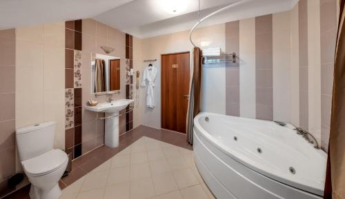 a bathroom with a tub and a toilet and a sink at Cronwell Nika Center in Omsk