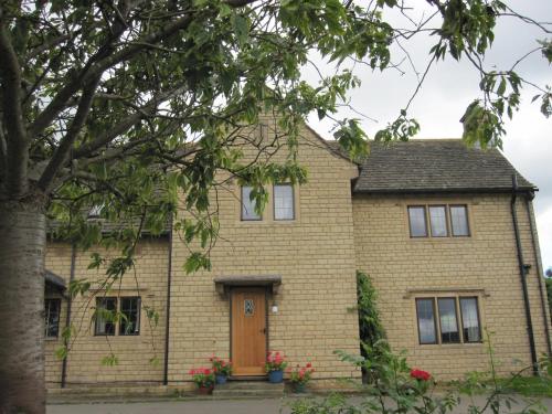 a yellow brick house with a brown door at Pardon Hill Farm B&B in Cheltenham