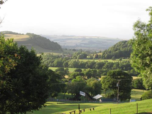 Blick auf ein grünes Feld mit Bäumen und Hügeln in der Unterkunft Pardon Hill Farm B&B in Cheltenham