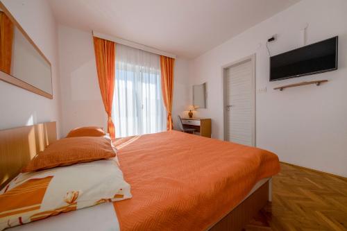 - une chambre avec un grand lit et une couverture orange dans l'établissement Lili Rab, à Rab