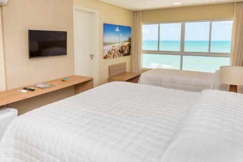 a hotel room with a bed and a television at Hotel Senac Barreira Roxa in Natal