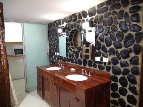 a bathroom with two sinks and a rock wall at Hotel Villa Sirena in Vichayito