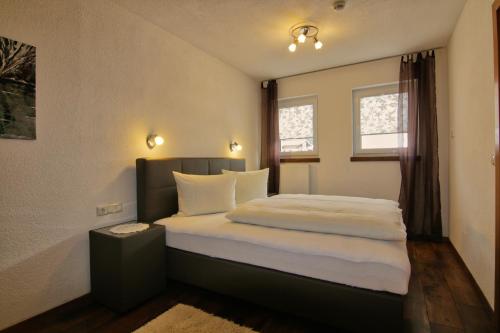 Schlafzimmer mit einem Bett mit weißer Bettwäsche und einem Fenster in der Unterkunft Haus Scheiber in Sankt Jakob in Defereggen