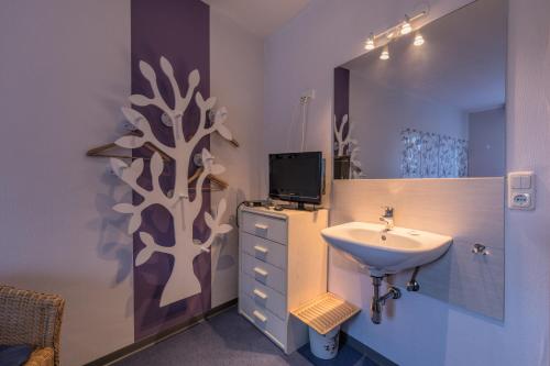 a bathroom with a sink and a tv on the wall at Hotel - Die kleine Zauberwelt in Braunlage