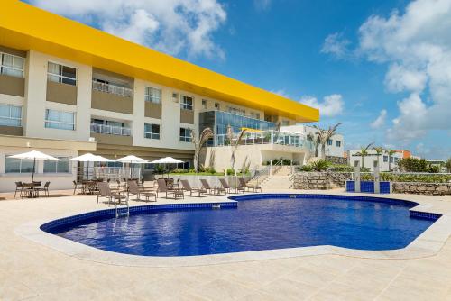 a hotel with a swimming pool in front of a building at Hotel Senac Barreira Roxa in Natal