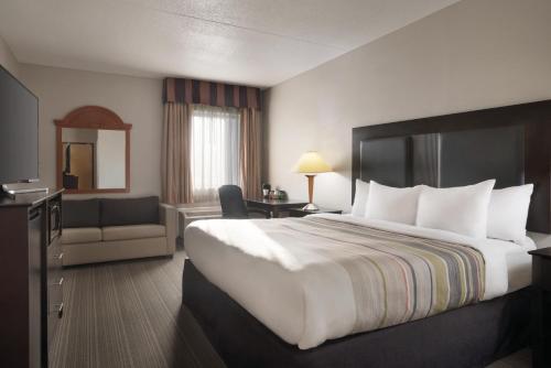 een hotelkamer met een groot bed en een bank bij Country Inn & Suites by Radisson, Indianapolis East, IN in Indianapolis