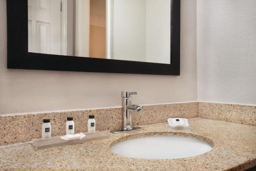 a bathroom sink in a hotel room with a mirror at Country Inn & Suites by Radisson, Indianapolis East, IN in Indianapolis